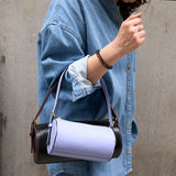 16 of 16:Person holding a black and white handbag against a neutral background