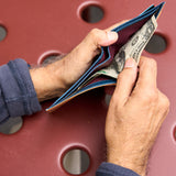 15 of 20:A close-up of a person's hands holding an open slim wallet with U.S.