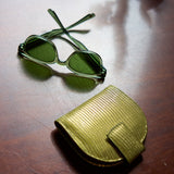 2 of 28:Green cat-eye sunglasses with a matching textured green case, displayed on a dark brown wooden surface.
