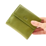 2 of 44:An olive green TUSK leather wallet held by a hand against a plain white background.