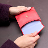 5 of 8:Red leather wallet held by a person against a dark background