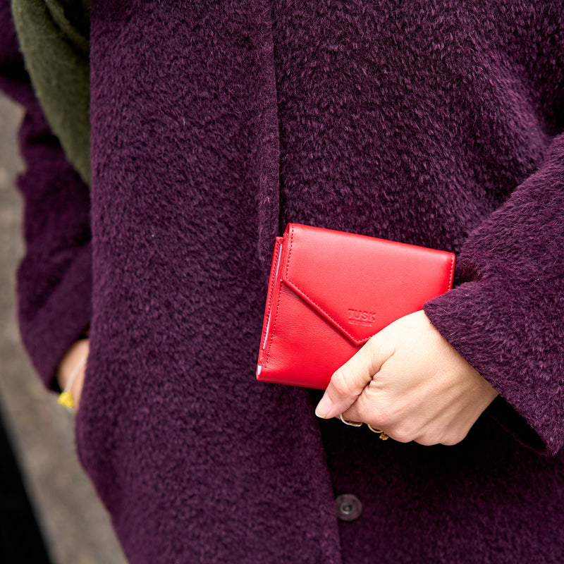 Person holding a red wallet against a purple coat