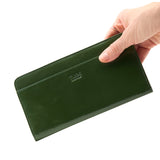 15 of 55:A dark green leather long wallet held by a hand against a plain white background. The brand name 'TUX' is debossed on the front.