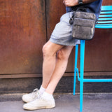 2 of 10:Person sitting on a blue chair wearing shorts and white sneakers, with a brown wall in the background.