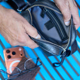 5 of 10:Person holding a black leather bag with a blue background