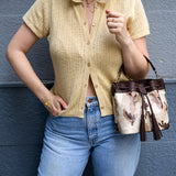 23 of 29:Person wearing a yellow knit shirt and blue jeans, holding a patterned handbag against a gray background - WHITE/BLACK#5