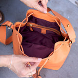 13 of 23:Person holding an orange leather handbag with a blurred background