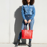 2 of 5:Woman holding a red bag against a light gray wall
