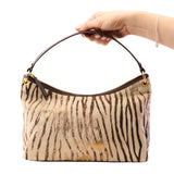 6 of 17:Handbag with zebra pattern held by a hand on a white background