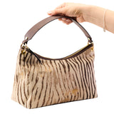 7 of 17:Handbag with zebra print pattern held by a hand on a white background