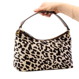 15 of 17:Leopard print handbag held by a hand on a white background