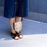 2 of 15:Person wearing brown sandals and a zebra-patterned bag on a sidewalk.