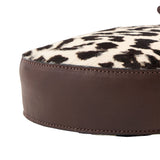 14 of 15:Round cushion with brown leather exterior and leopard print interior on a white background