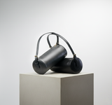 3 of 13:Black cylindrical handbag on a white pedestal against a light gray background