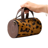 4 of 43:Leopard print handbag with brown leather accents held by a hand on a white background