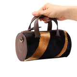 19 of 43:Hand holding a cylindrical bag with brown, black, and beige stripes on a white background