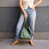 3 of 15:Person holding a green bag against a gray wall