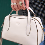 4 of 10:White handbag held by a person with a blurred background