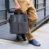 7 of 20:Person holding a black leather bag on a city street