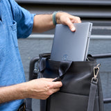 8 of 20:Person placing a laptop into a black leather bag.