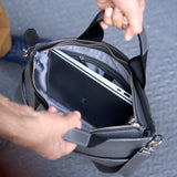 9 of 20:Person opening a black leather briefcase to reveal a laptop inside.