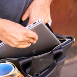 5 of 16:Person placing a tablet into a black leather briefcase with a blurred background