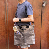 6 of 16:Person holding a gray leather bag against a wooden door.