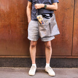 8 of 16:Man standing against a rusted metal wall wearing a blue shirt, gray shorts, and white sneakers.