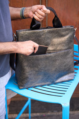 9 of 16:Person holding a dark leather bag on a blue chair