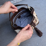 29 of 29:Person opening a camouflage-patterned handbag with a brown handle on a gray pavement background WHITE/BLACK#5