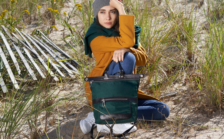 Image , Woman with bag sitting in dunes near wooden slats.
